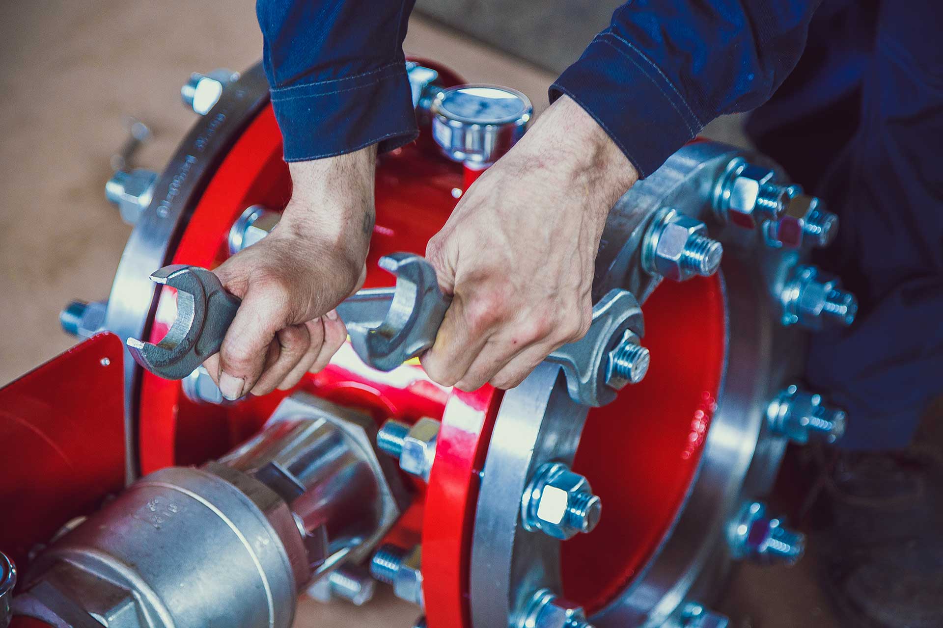 Arbeiter montiert mit Schraubenschlüssel ein rotes Ventil