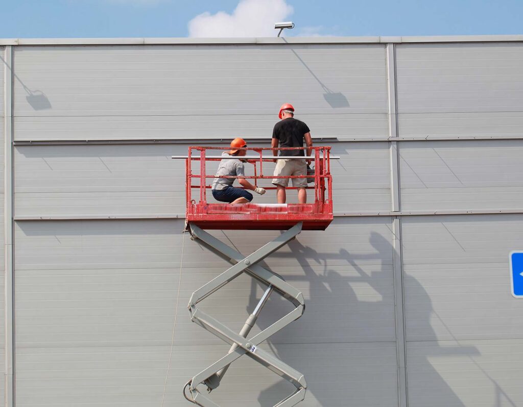 Arbeiter auf Hebebühne an einer Gebäudewand
